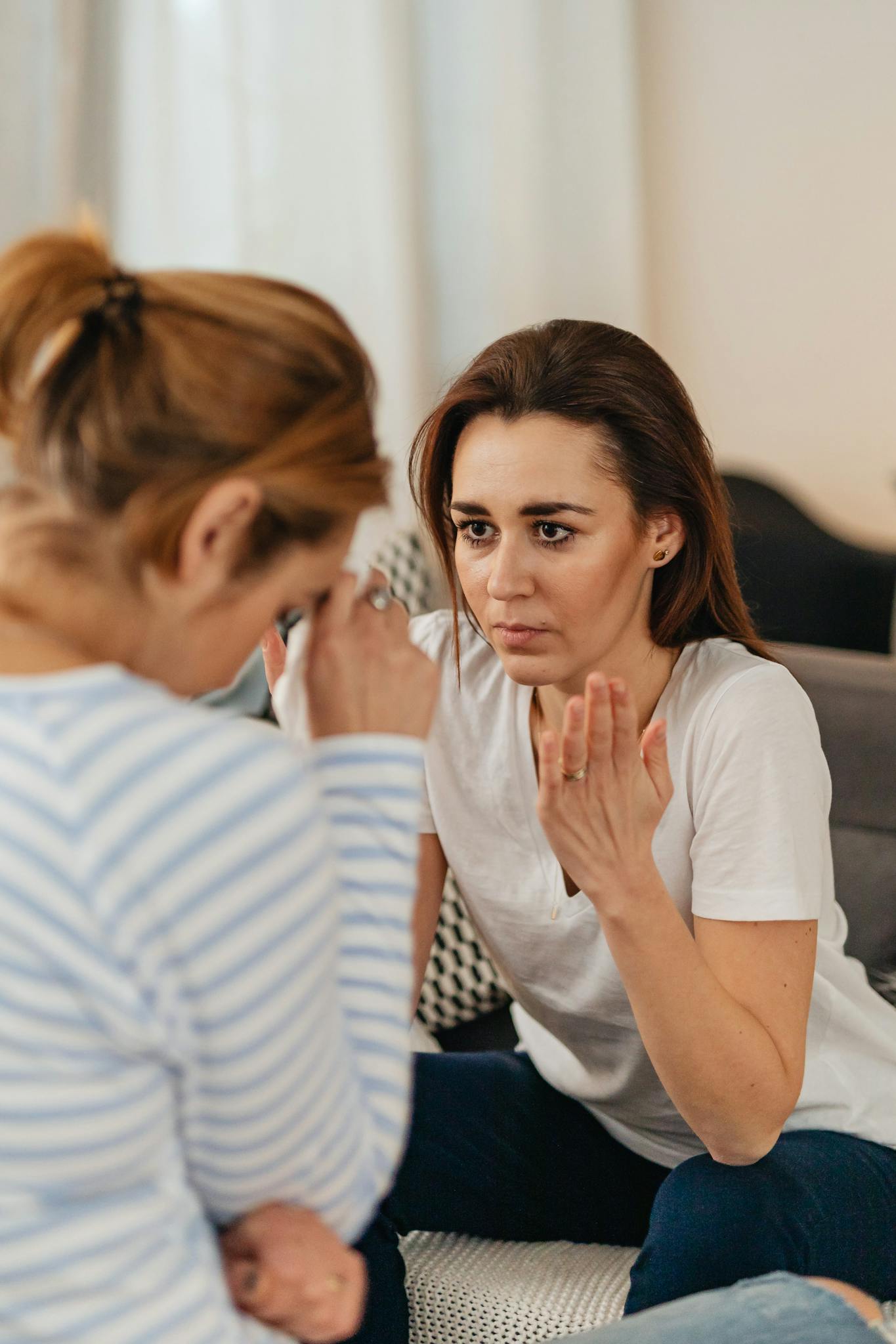 Two women engaged in an intense emotional discussion indoors, conveying stress and concern.